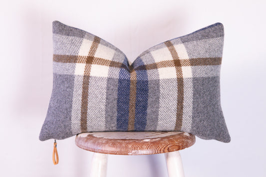 Plaid patterned pillow on a wooden stool against a white background