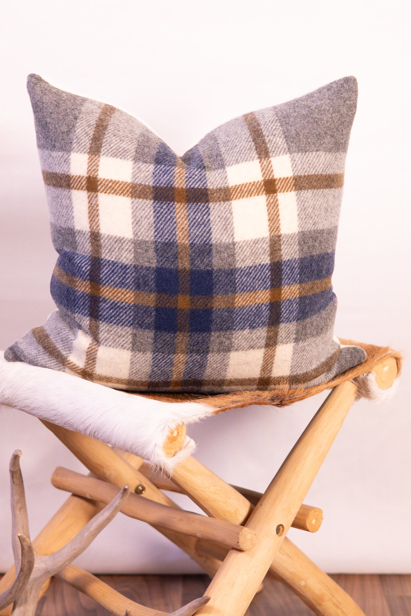 Plaid pillow on a wooden stool with a white background