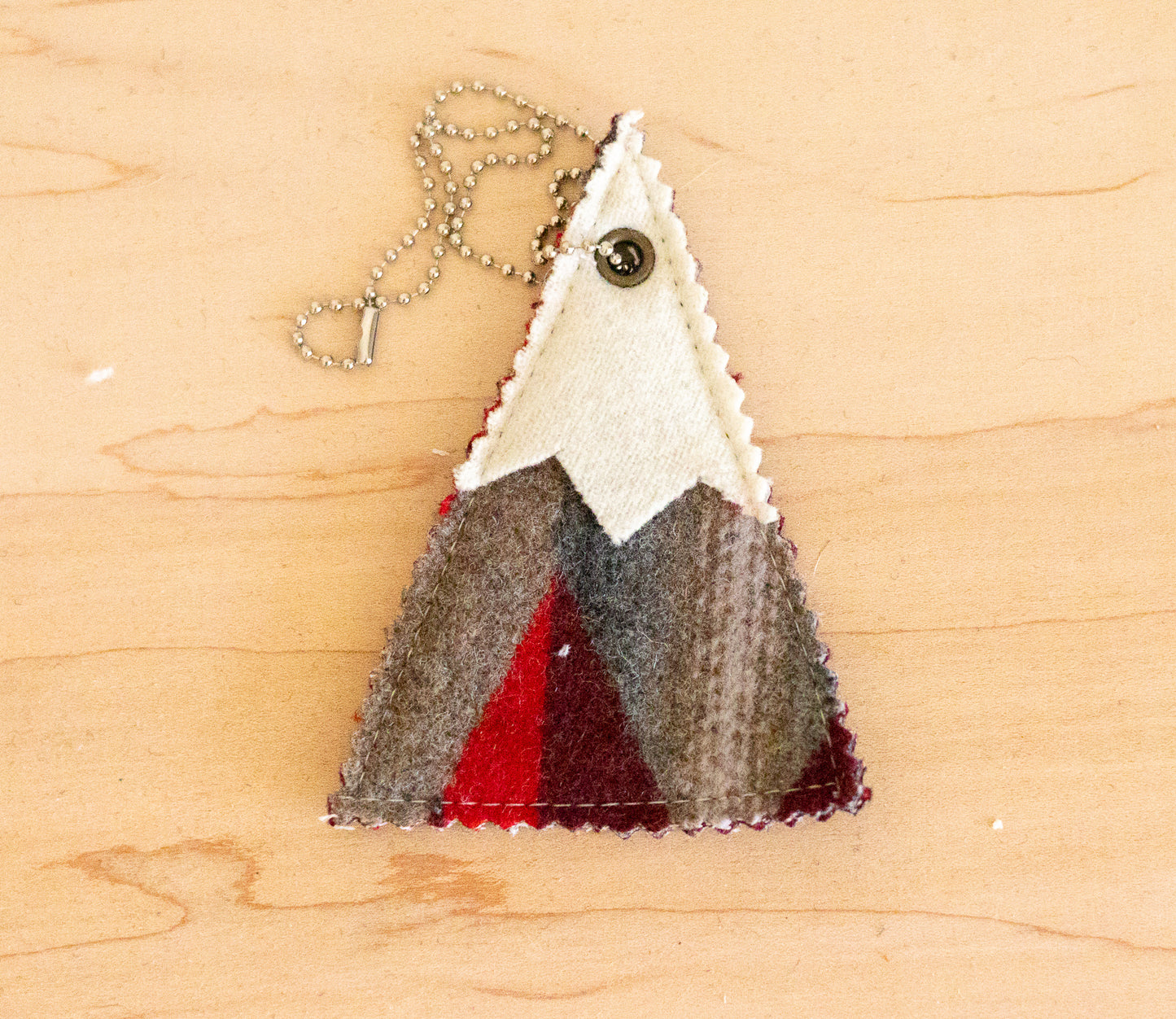 Triangular pendant with mountain design on a wooden surface