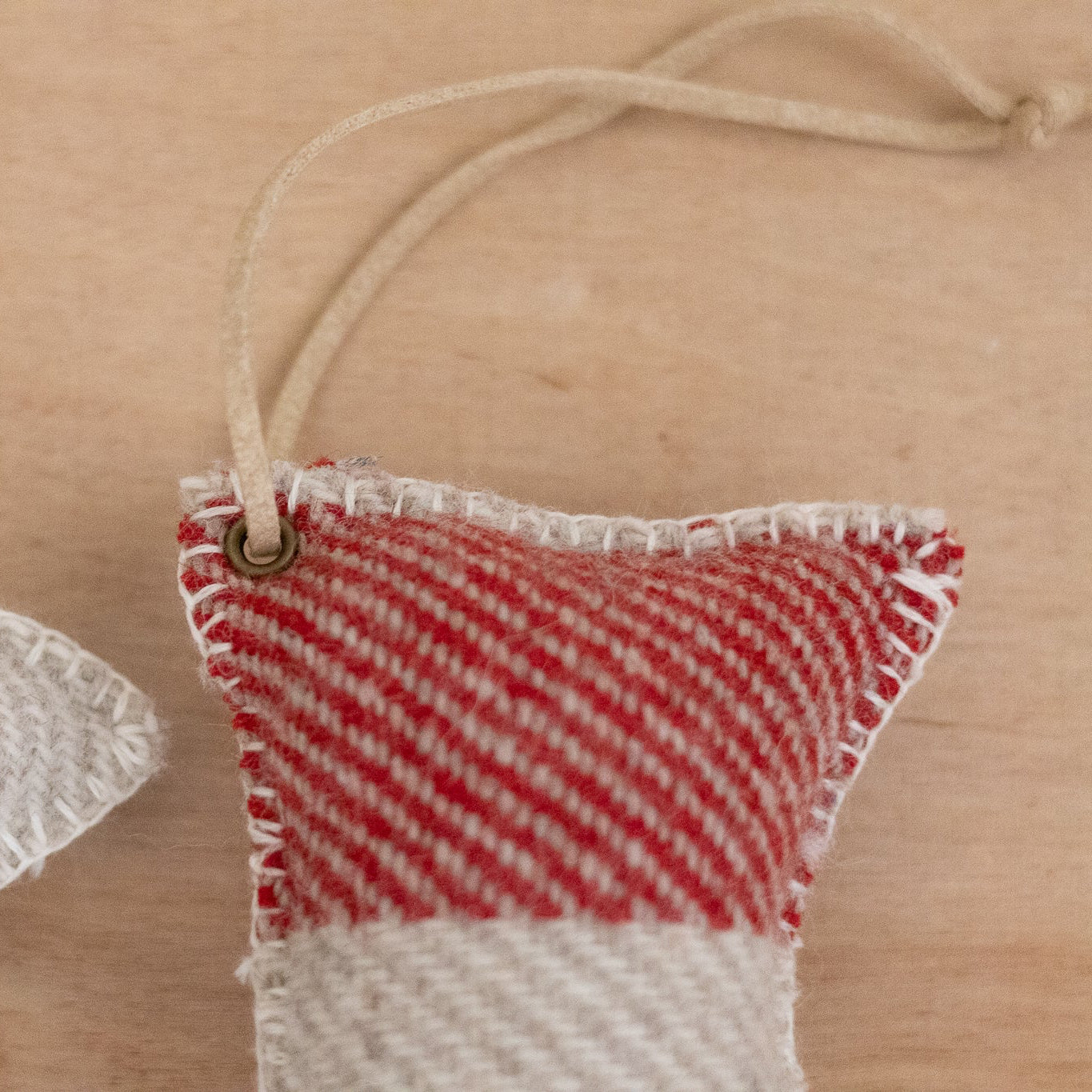 Woven wool ornaments with a red, white, and green stripe pattern on a wooden surface.
