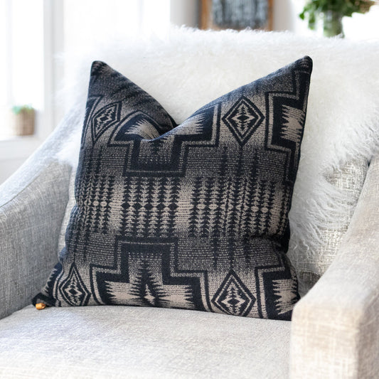 Decorative pillow with geometric black and light tan pattern on a comfortable white sofa