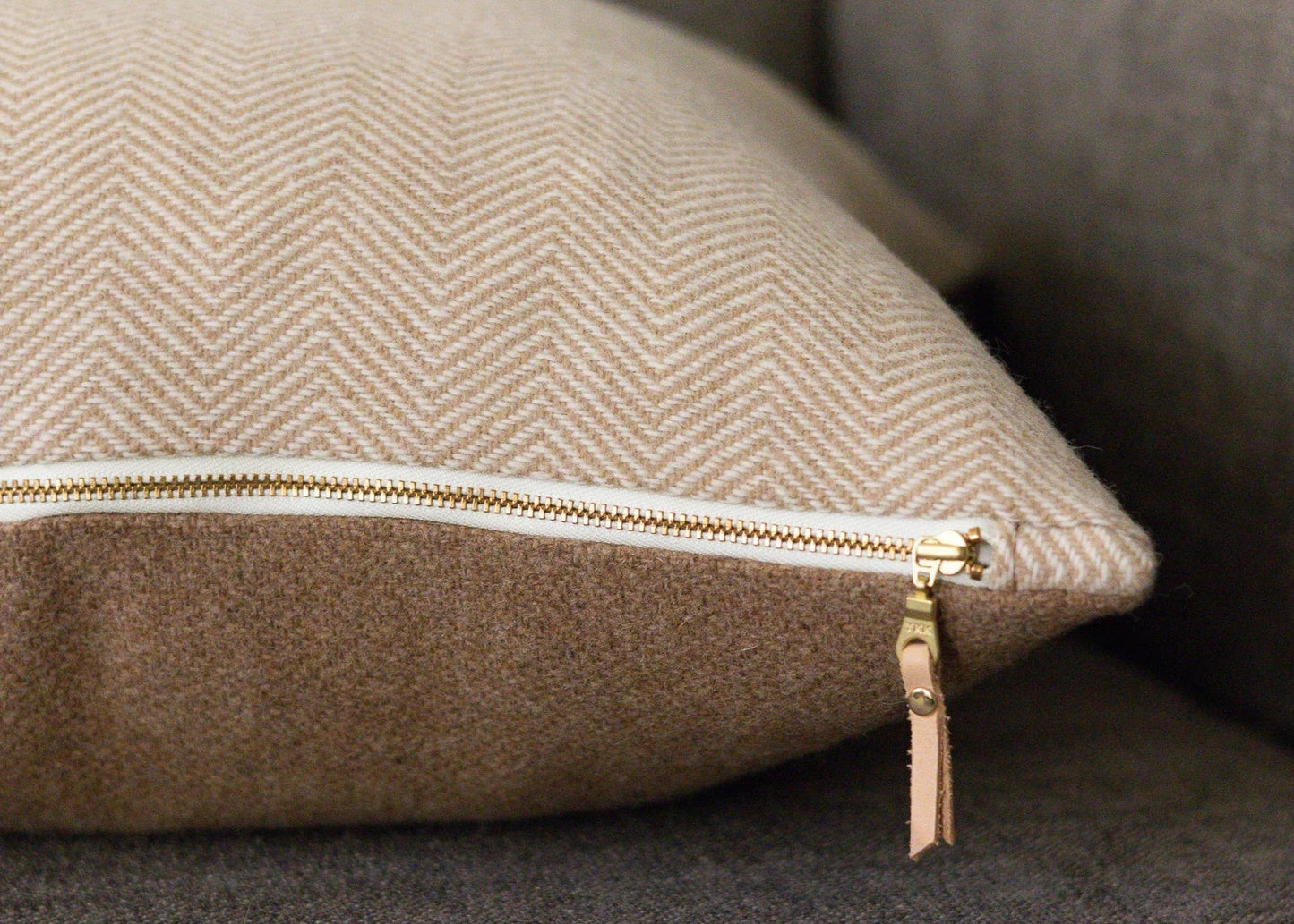 Beige cushion with a zipper on a gray sofa