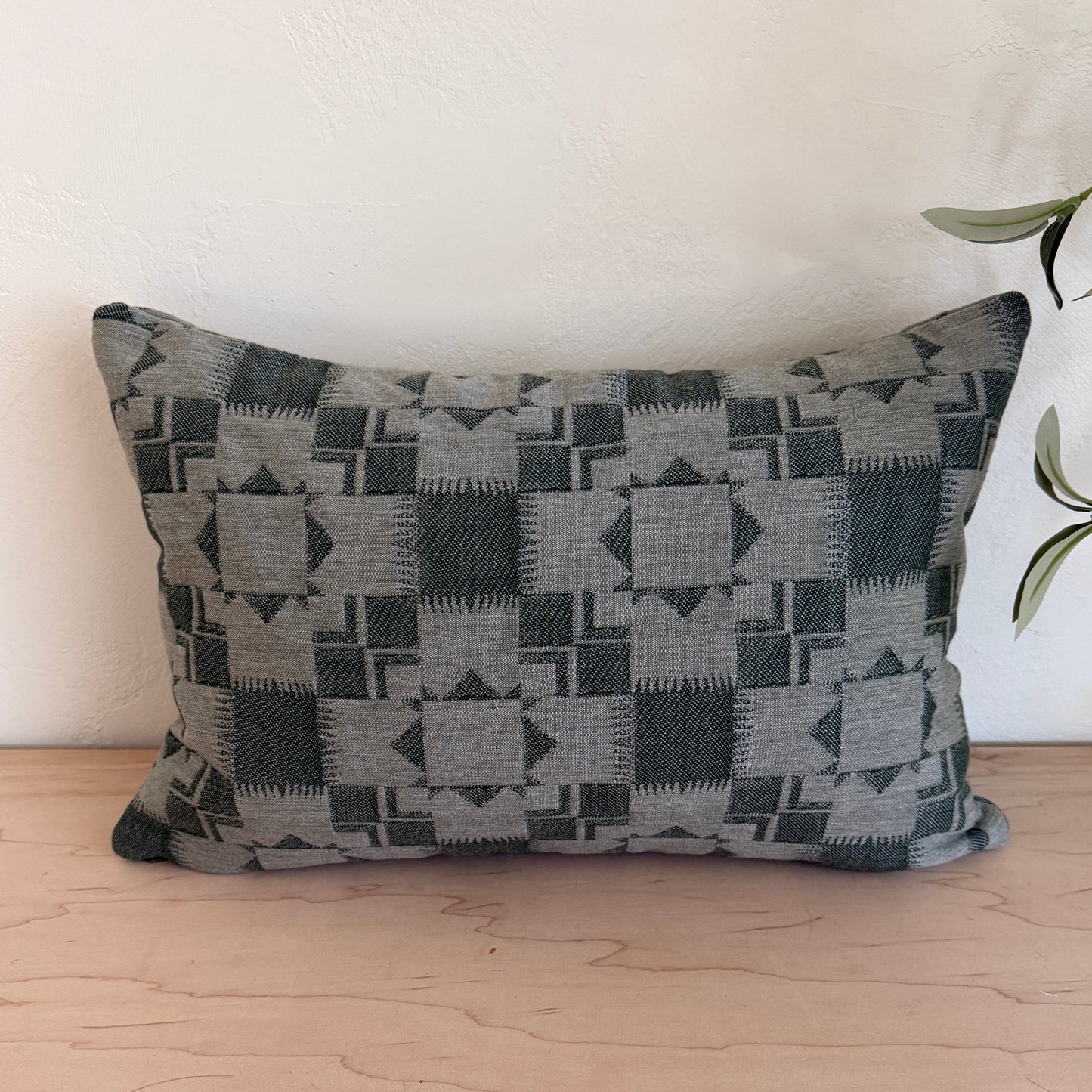 Decorative pillow with geometric pattern on a white couch next to a wooden wall.