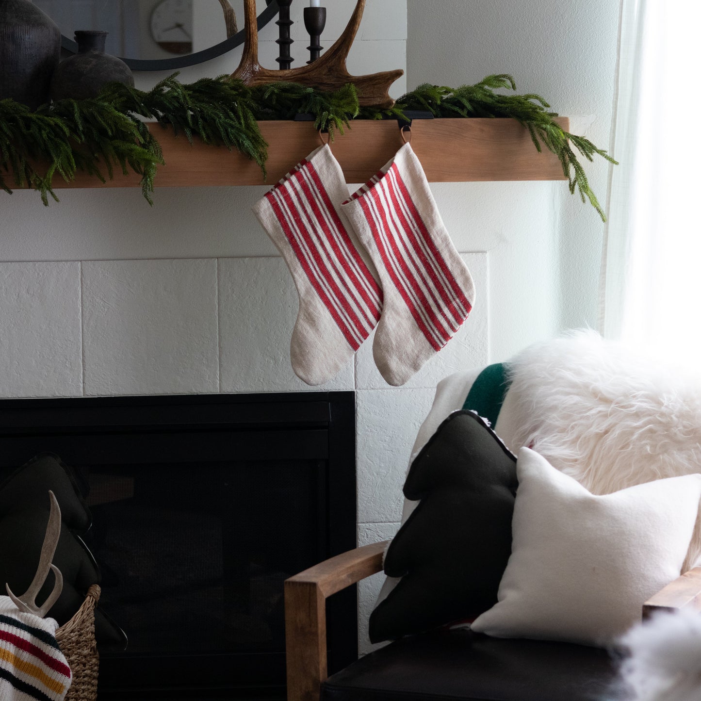 Christmas stockings hanging above a fireplace with festive decorations.