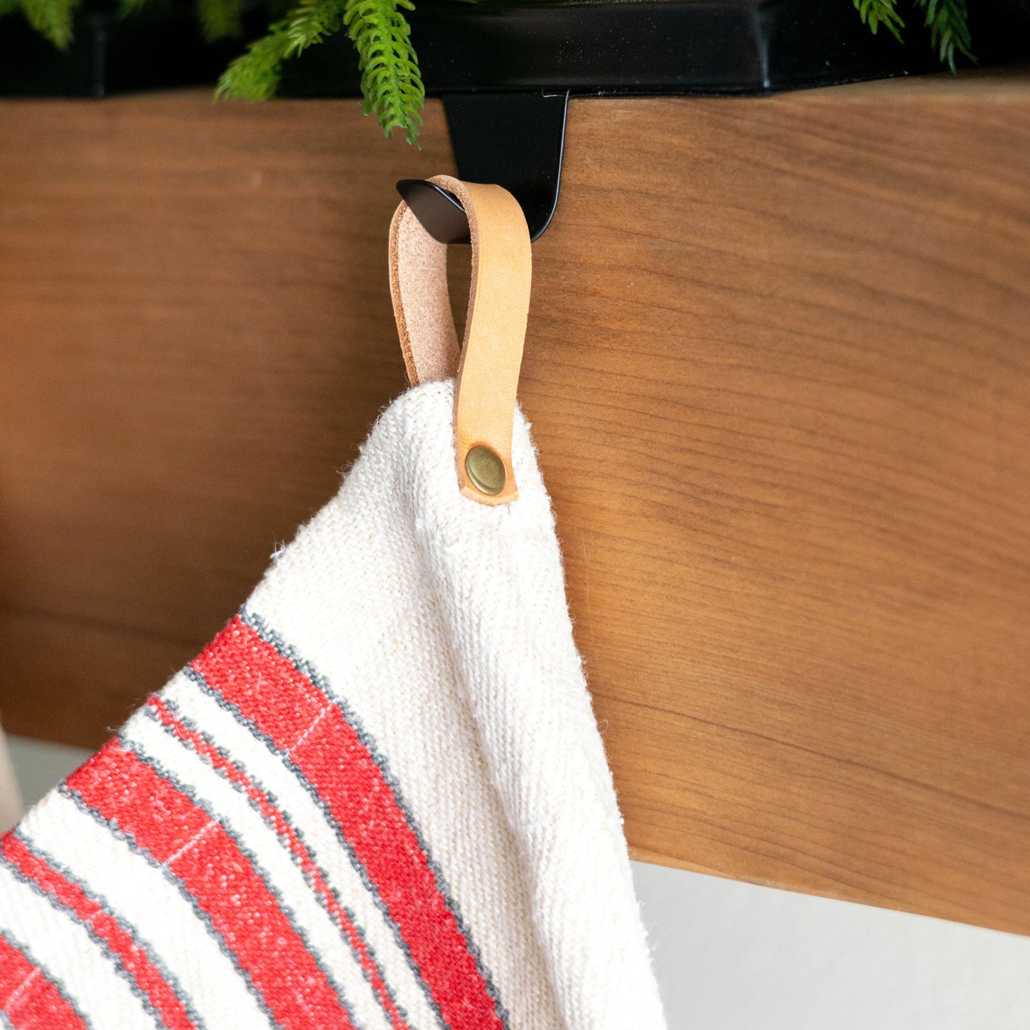 Close up of stocking hook against a wooden surface with plants in the background