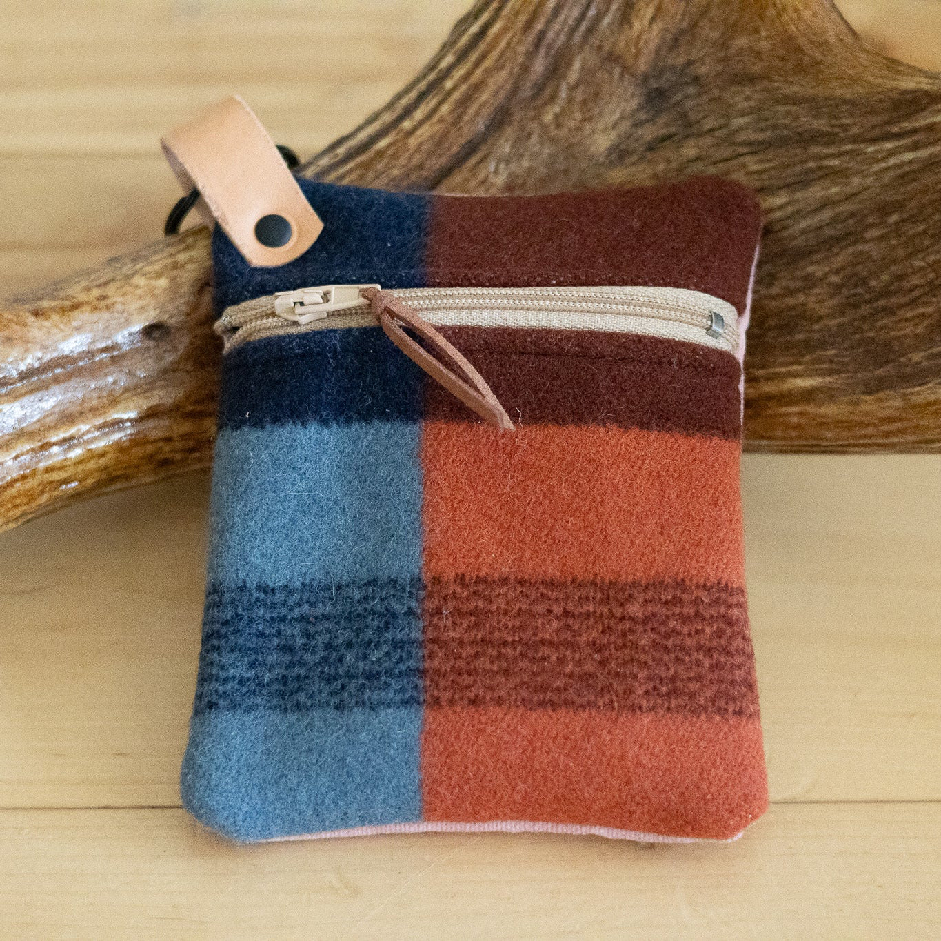 Colorful plaid pouch with leather strap on a wooden surface