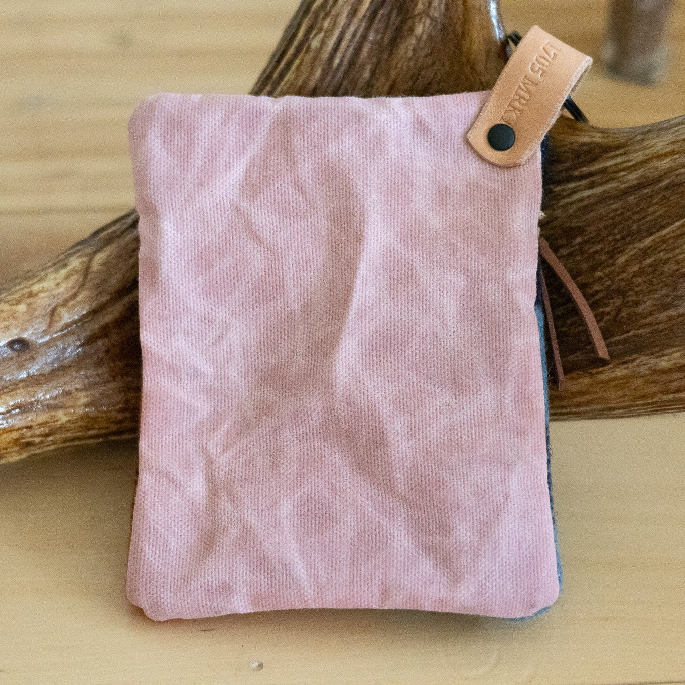 Pink fabric pouch with a leather tag on a wooden surface