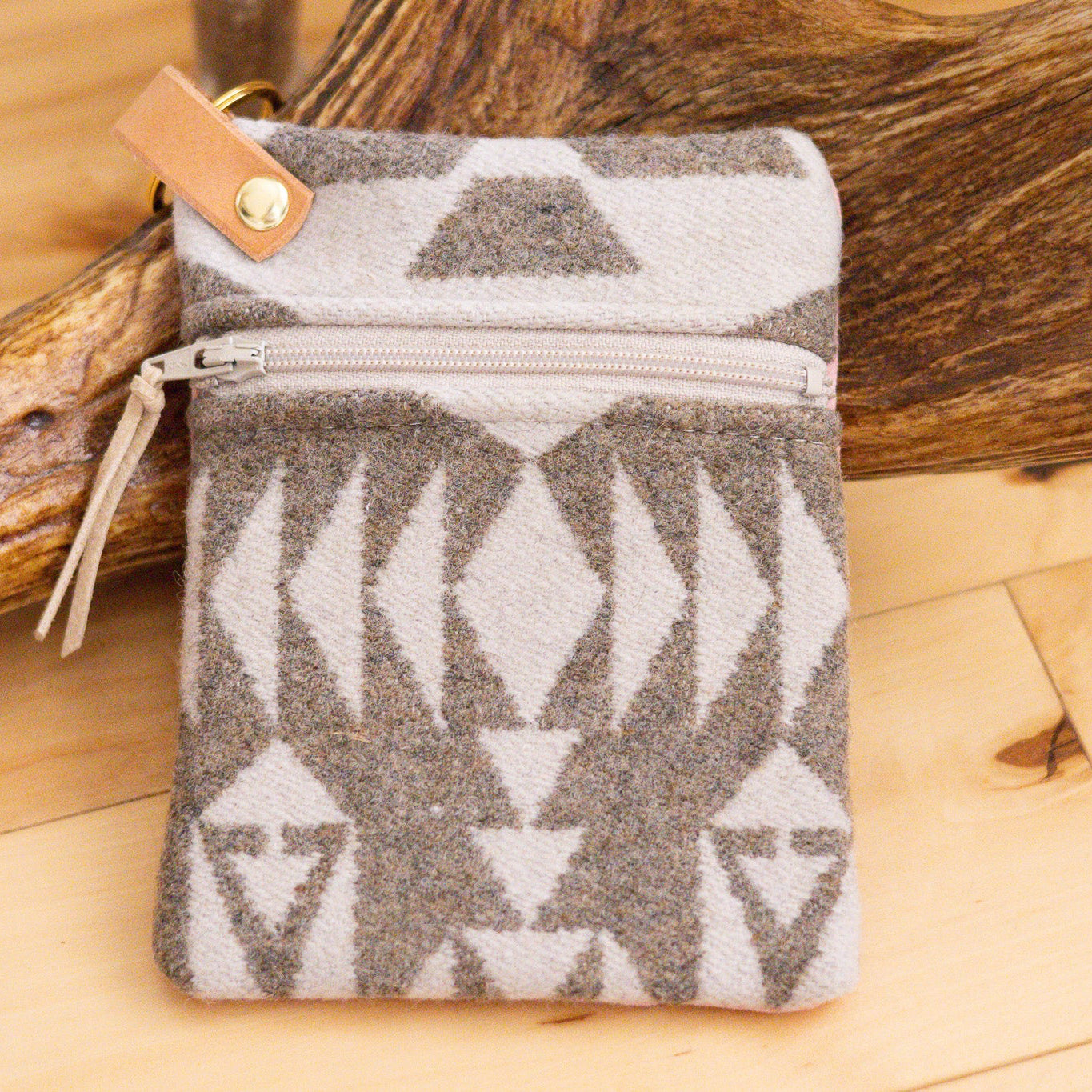 Patterned pouch with leather strap on wooden surface