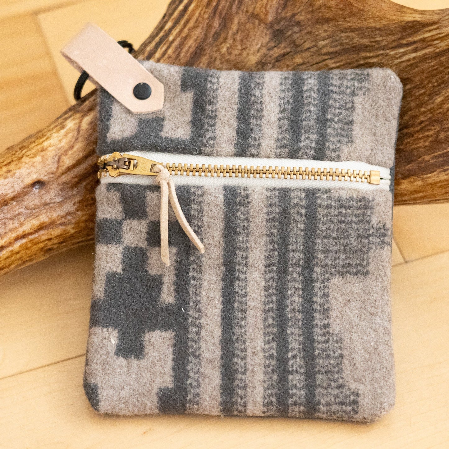 Small pouch with a checkered pattern and gold zipper on a wooden surface