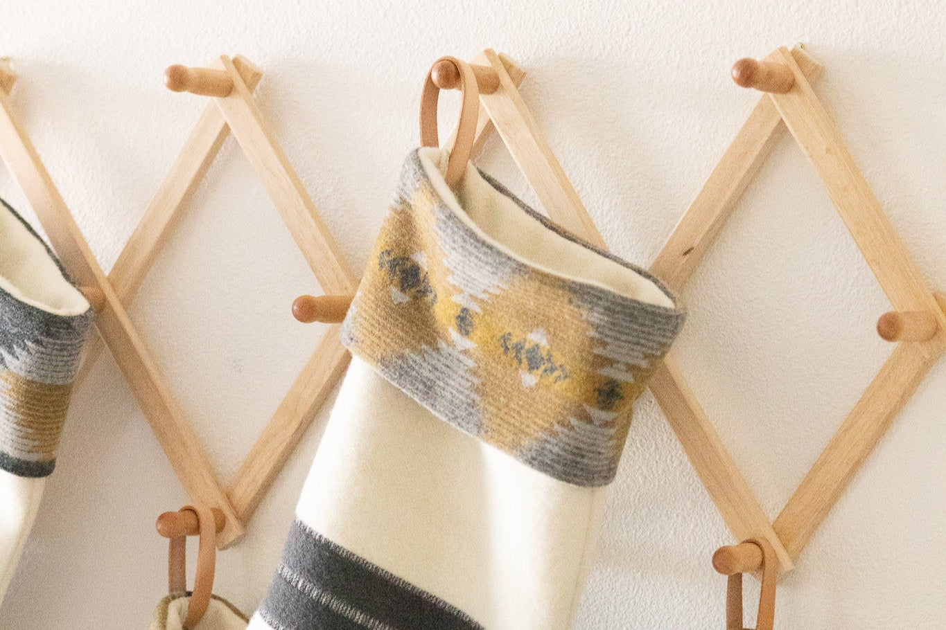 Decorative stockings with striped patterns hanging on a wooden rack.