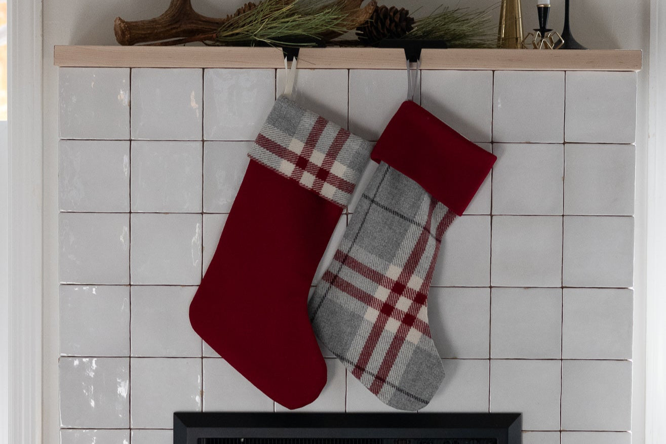 Red and gray plaid stockings hanging above a fireplace with decorative antlers on the mantel.