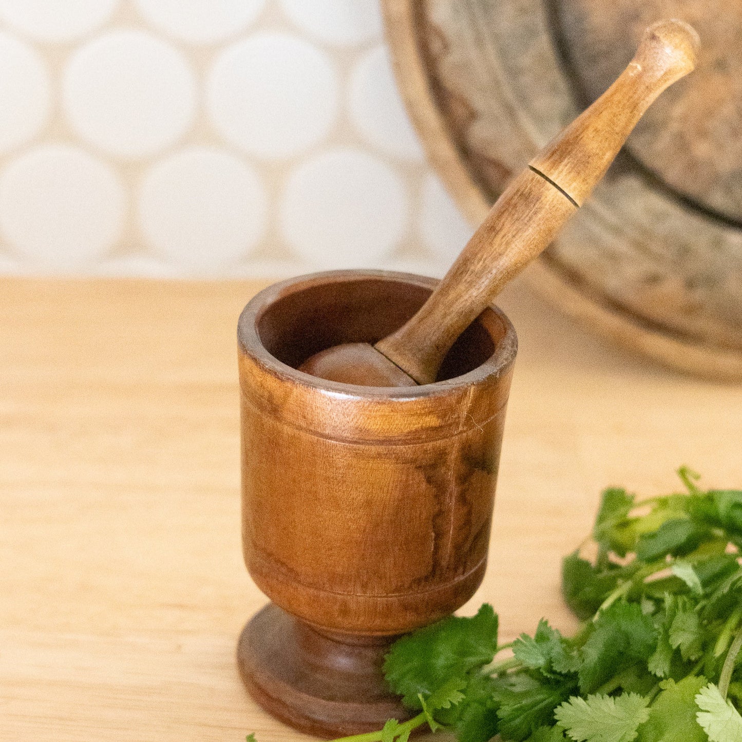 Wooden mortar and pestle with herbs on a wooden surface