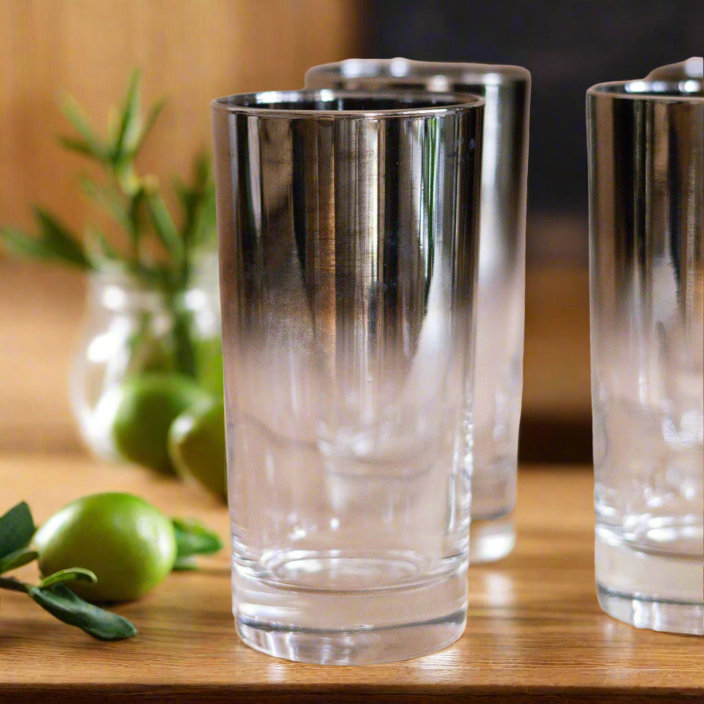 Set of four clear glasses with metallic rim on a wooden surface