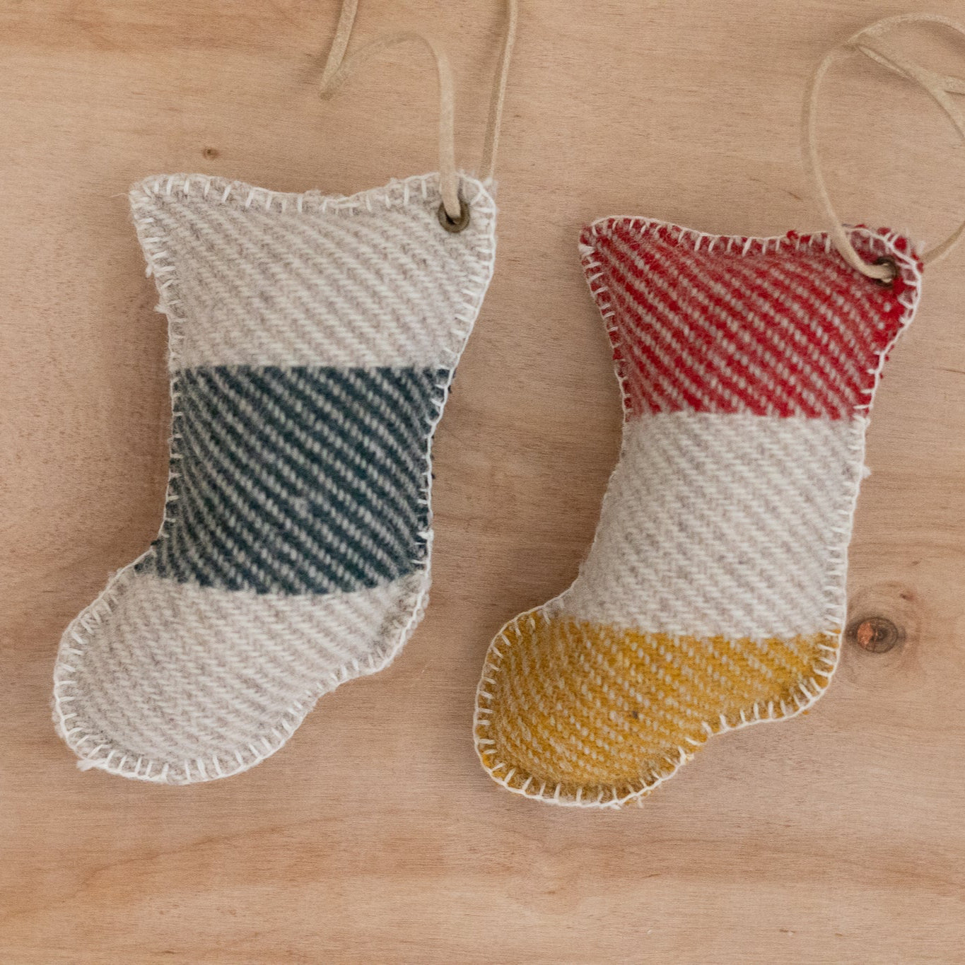 Two fabric stockings with striped patterns hanging on a wooden surface.