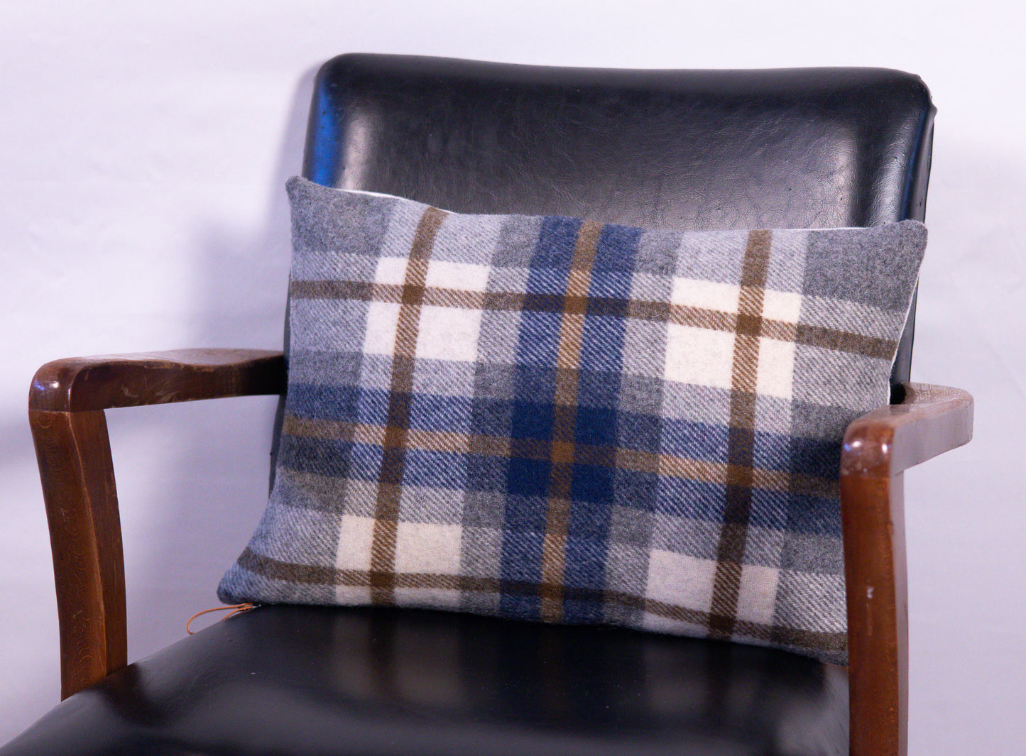 Plaid cushion on a black chair against a white background