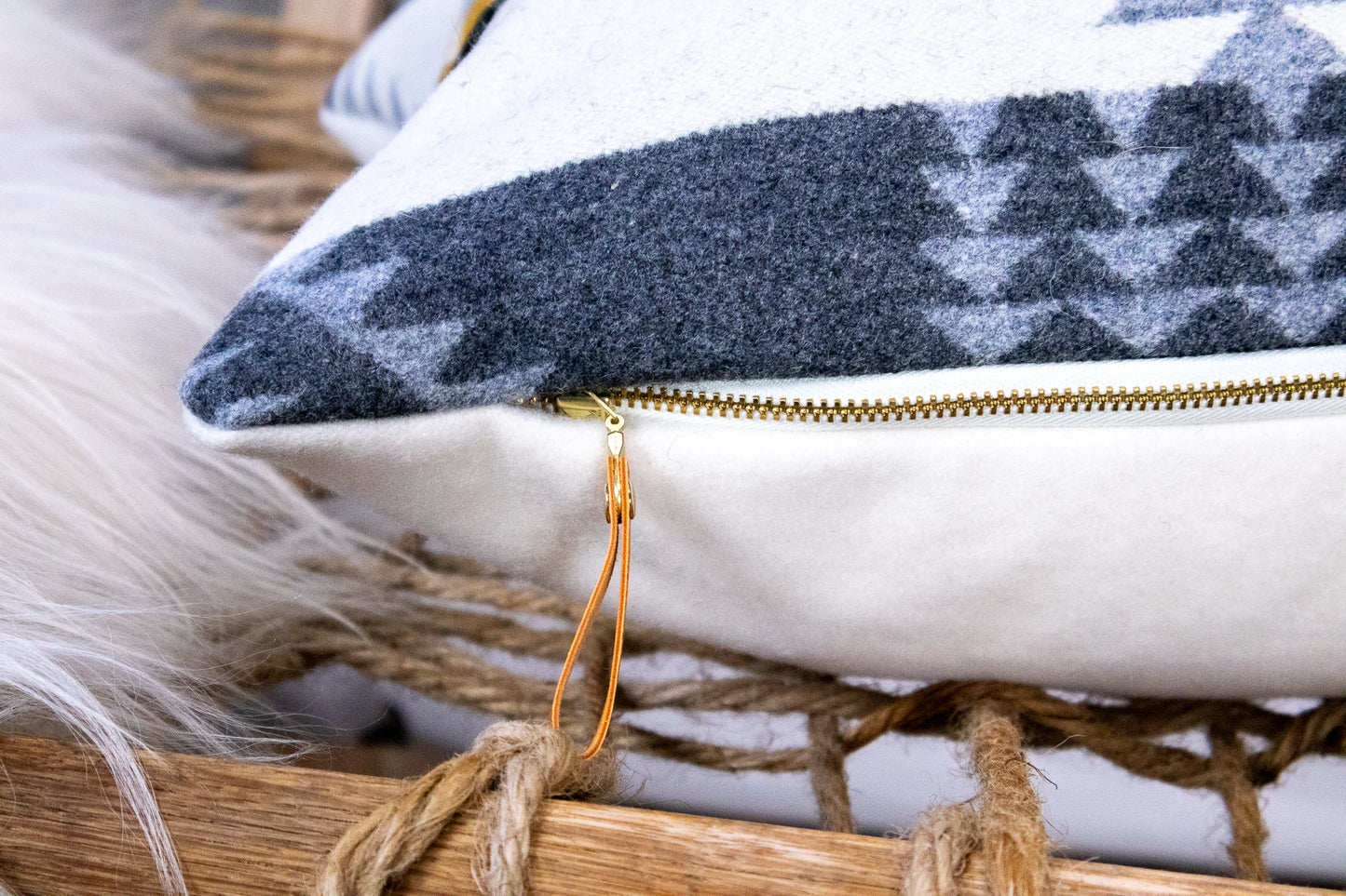 Close-up of a pillow cover with a metal exposed zipper and leather zipper pull