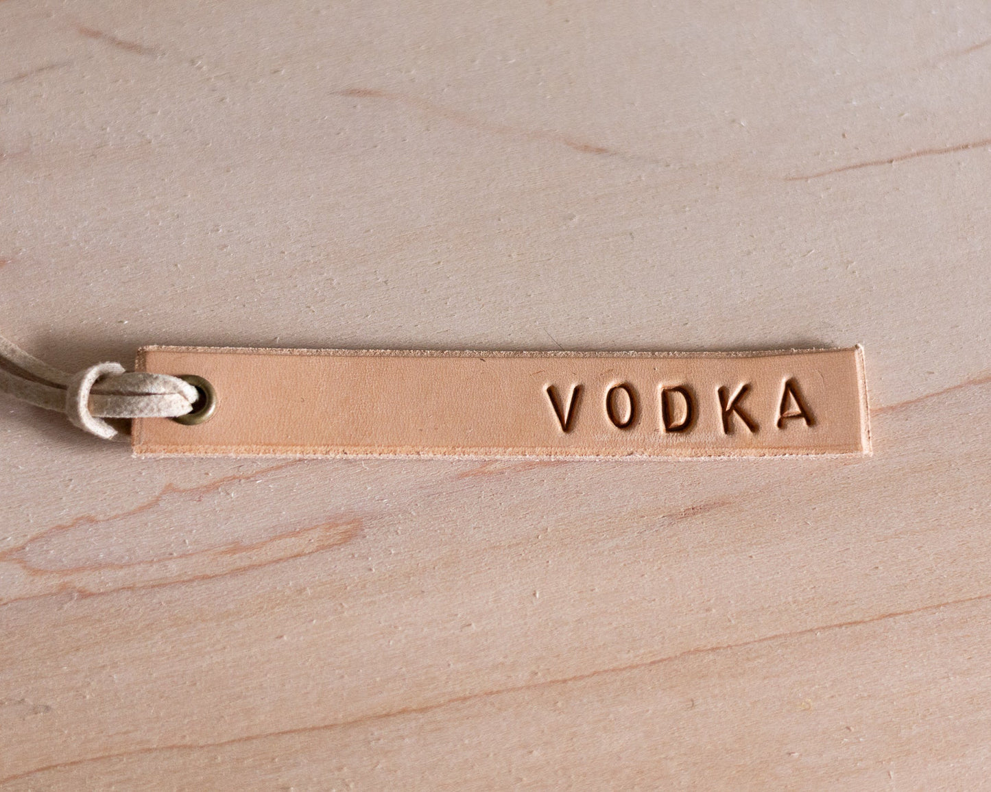 Leather tag with 'VODKA' engraving on a wooden surface