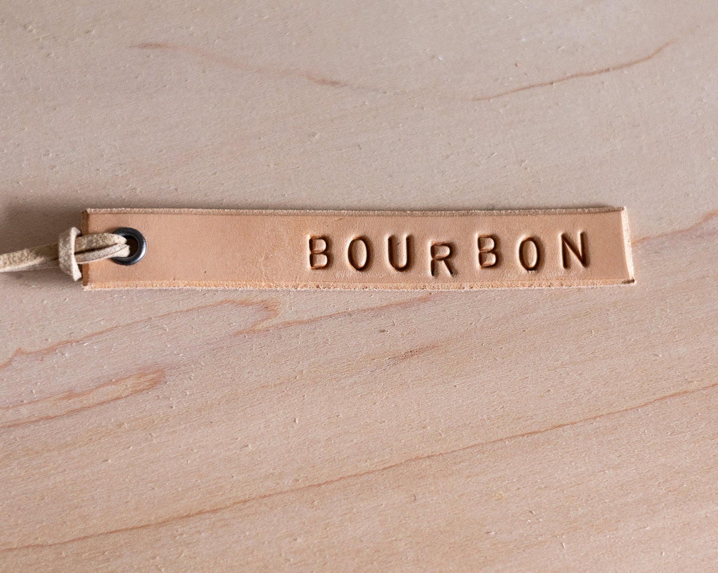 Leather tag with 'BOURBON' engraving on a wooden surface