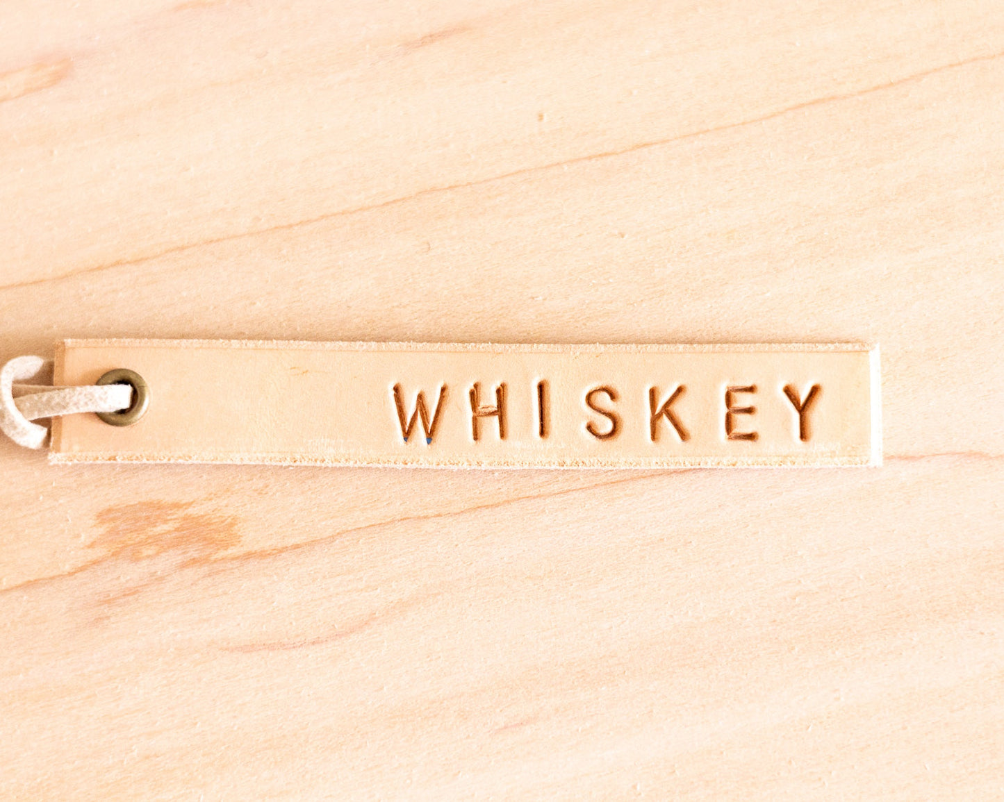 Leather tag with 'WHISKEY' engraving on a wooden background