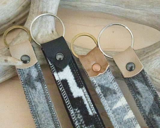 Three keychains with leather straps on a wooden surface