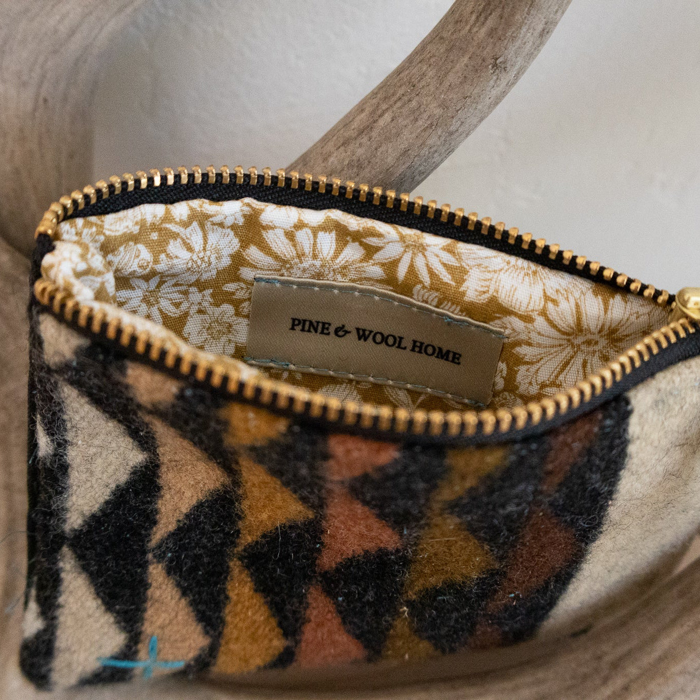 Small pouch with geometric pattern and gold zipper on a wooden surface
