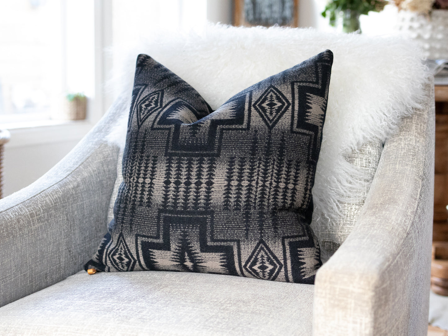 Decorative pillow with geometric black and light tan pattern on a comfortable white sofa