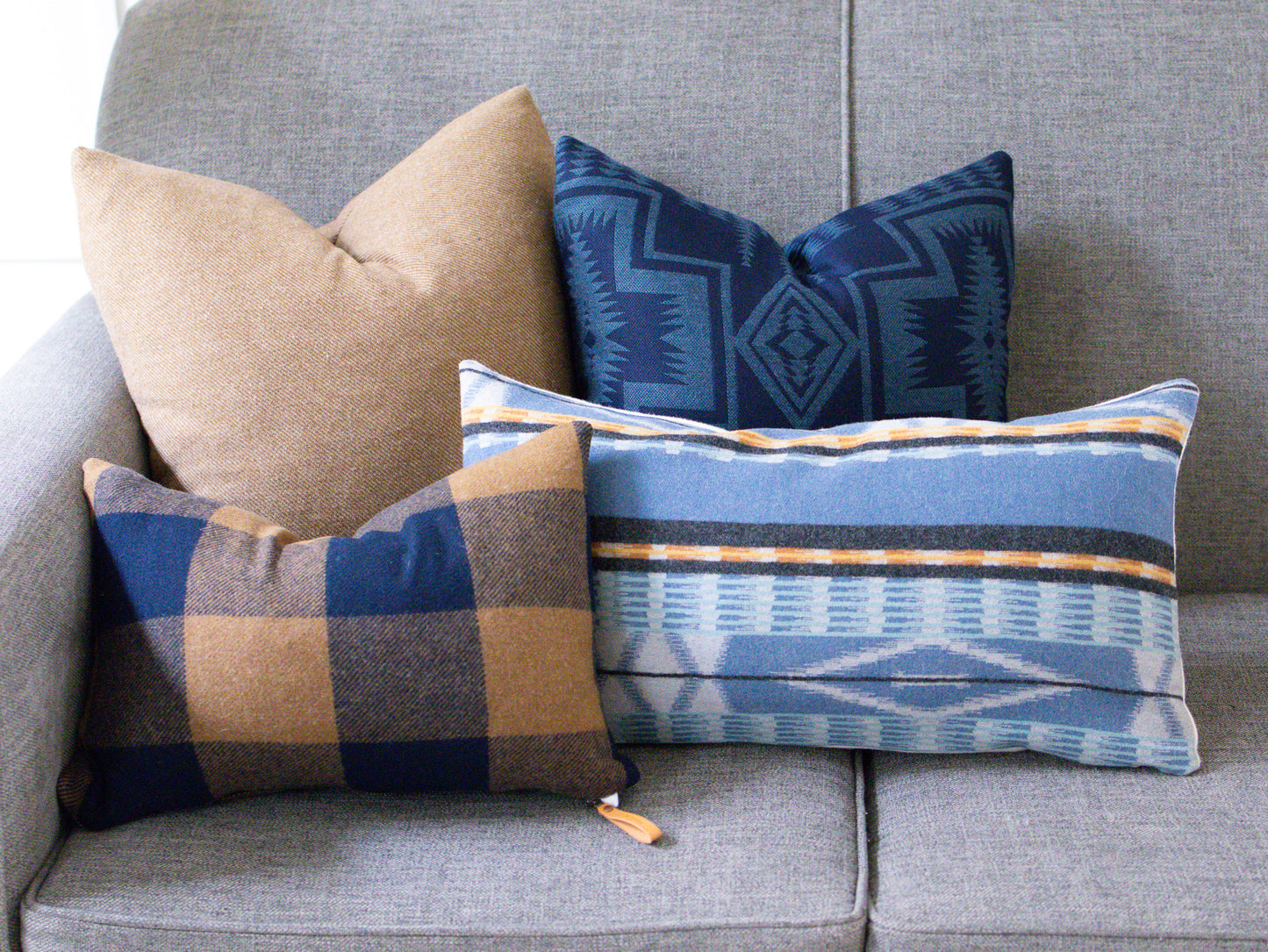 Four patterned pillows on a gray sofa