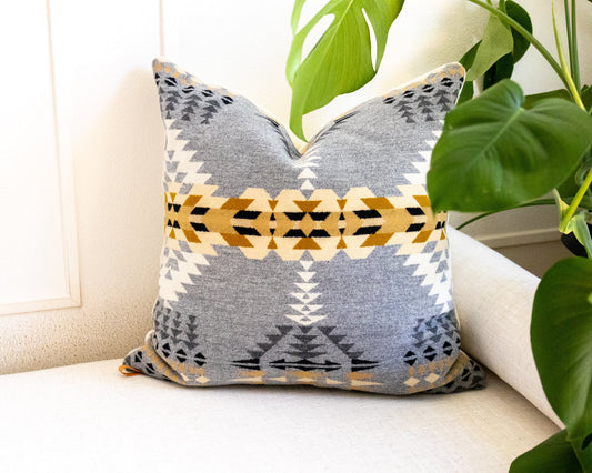 Decorative pillow with geometric pattern on a white couch with plants in the background