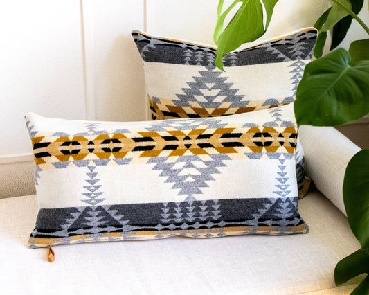 Decorative pillows with geometric patterns on a couch next to a plant