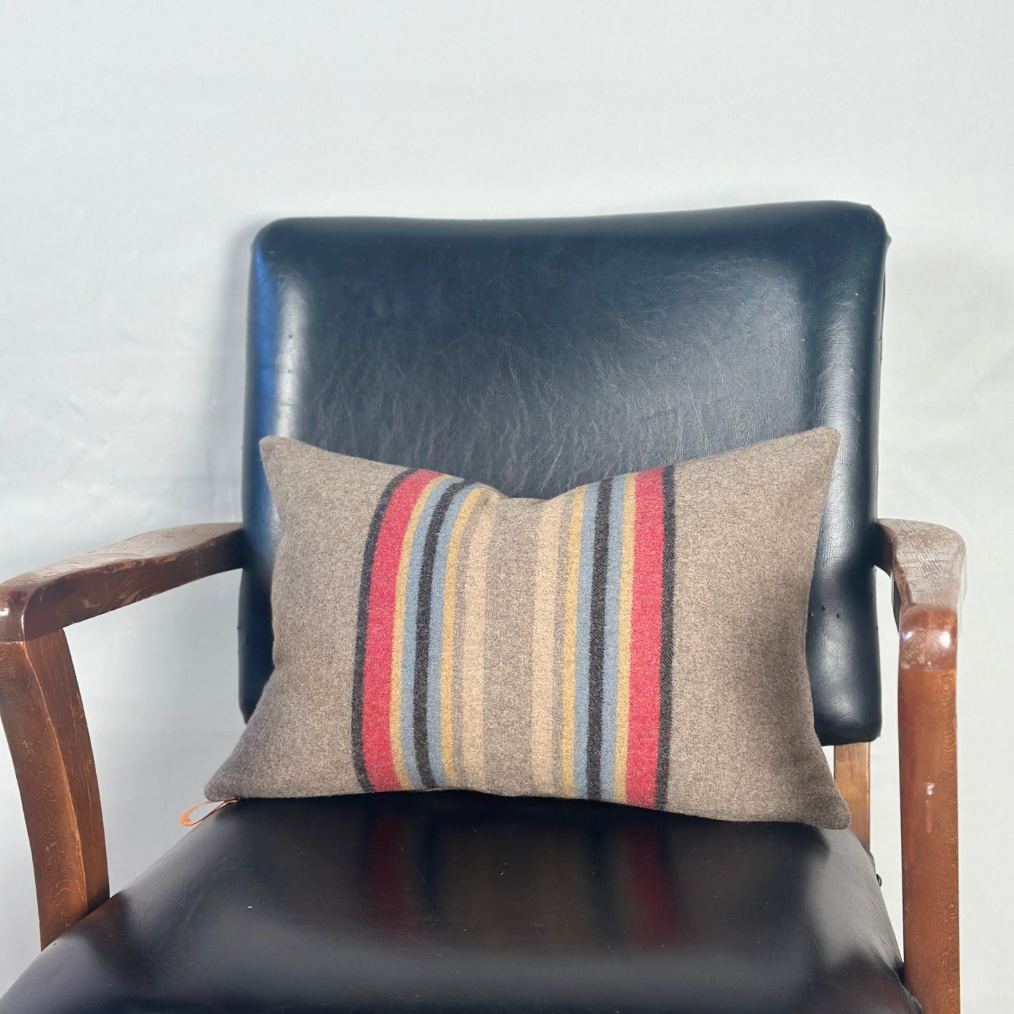 Striped pillow on a black leather chair against a white wall