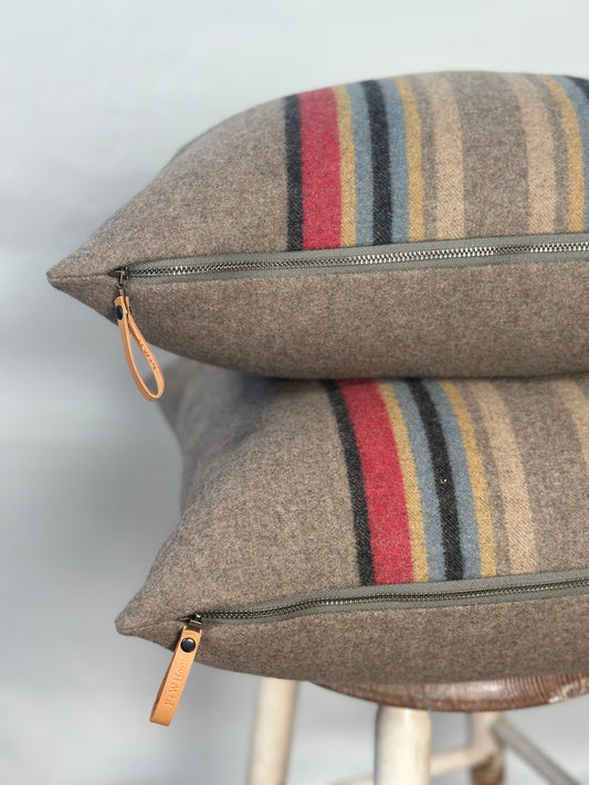 Two striped pillows with leather zipper pulls on a light background