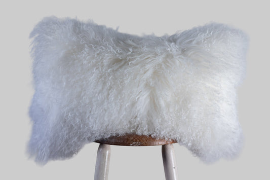 White fluffy pillow on a wooden stool against a gray background