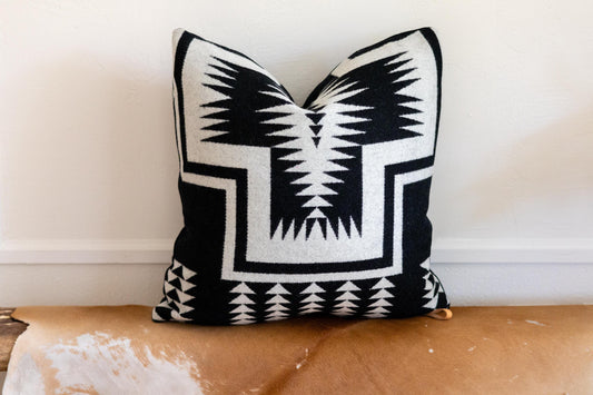 Black and white patterned pillow on a wooden surface with a neutral background