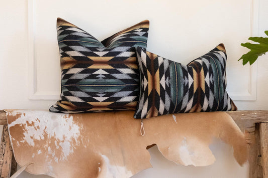 Two patterned pillows on a wooden bench with a cowhide rug
