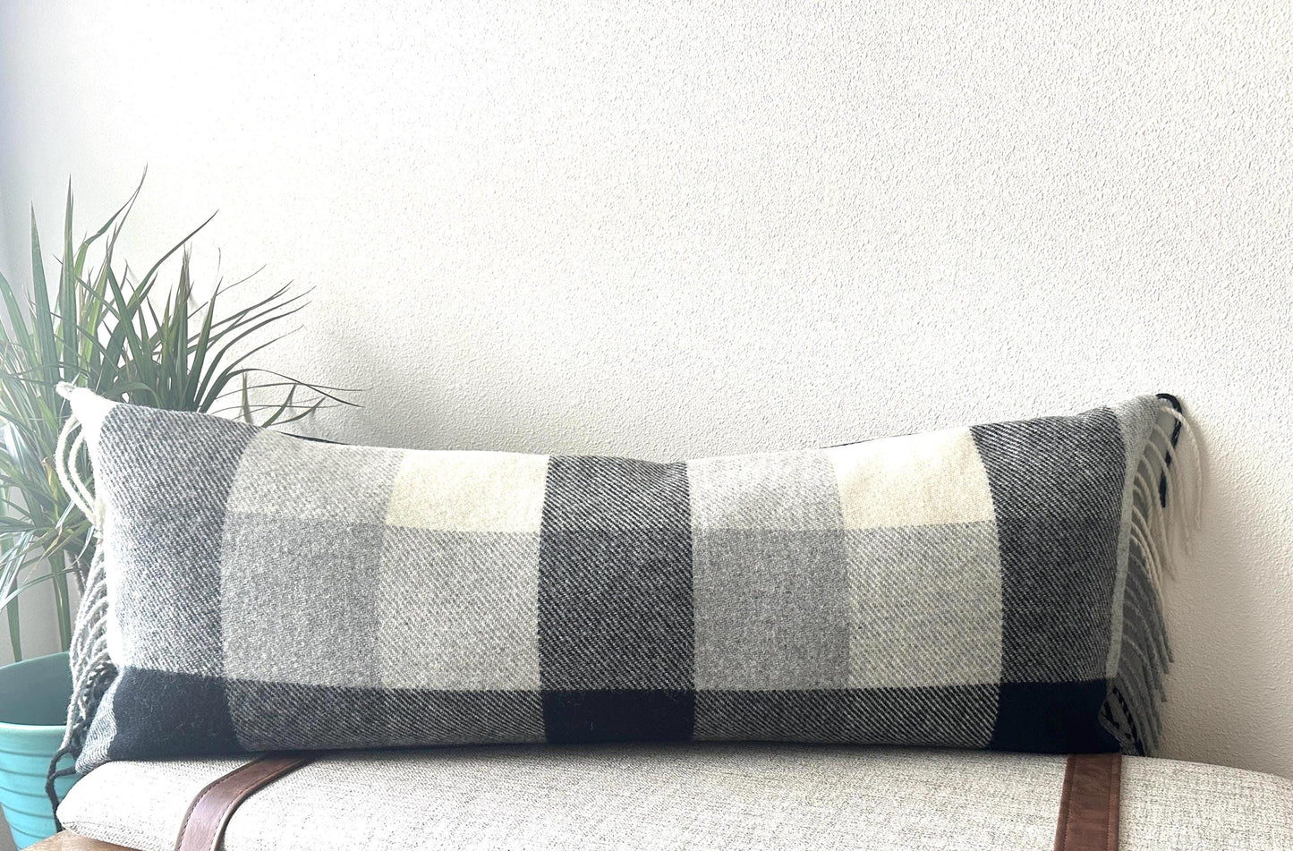 Plaid lumbar pillow on a couch with a plant in the background