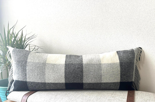 Plaid lumbar pillow on a couch with a plant in the background