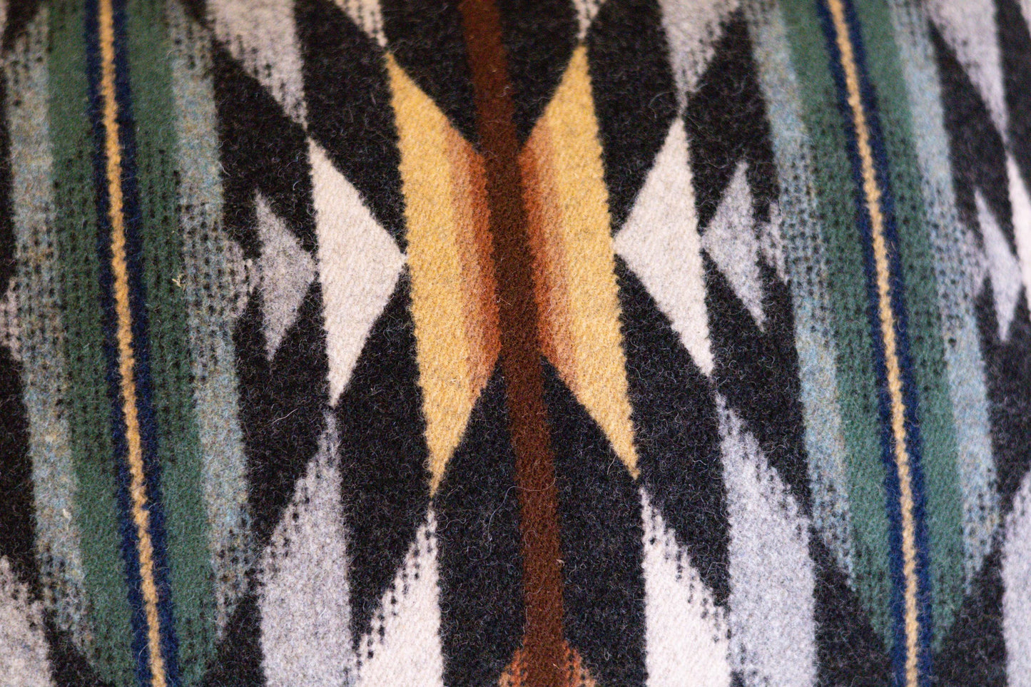 Close-up of a patterned fabric with geometric design in black, yellow, and blue.