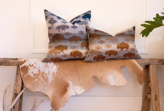 Decorative pillows with animal pattern on a wooden bench with cowhide rug