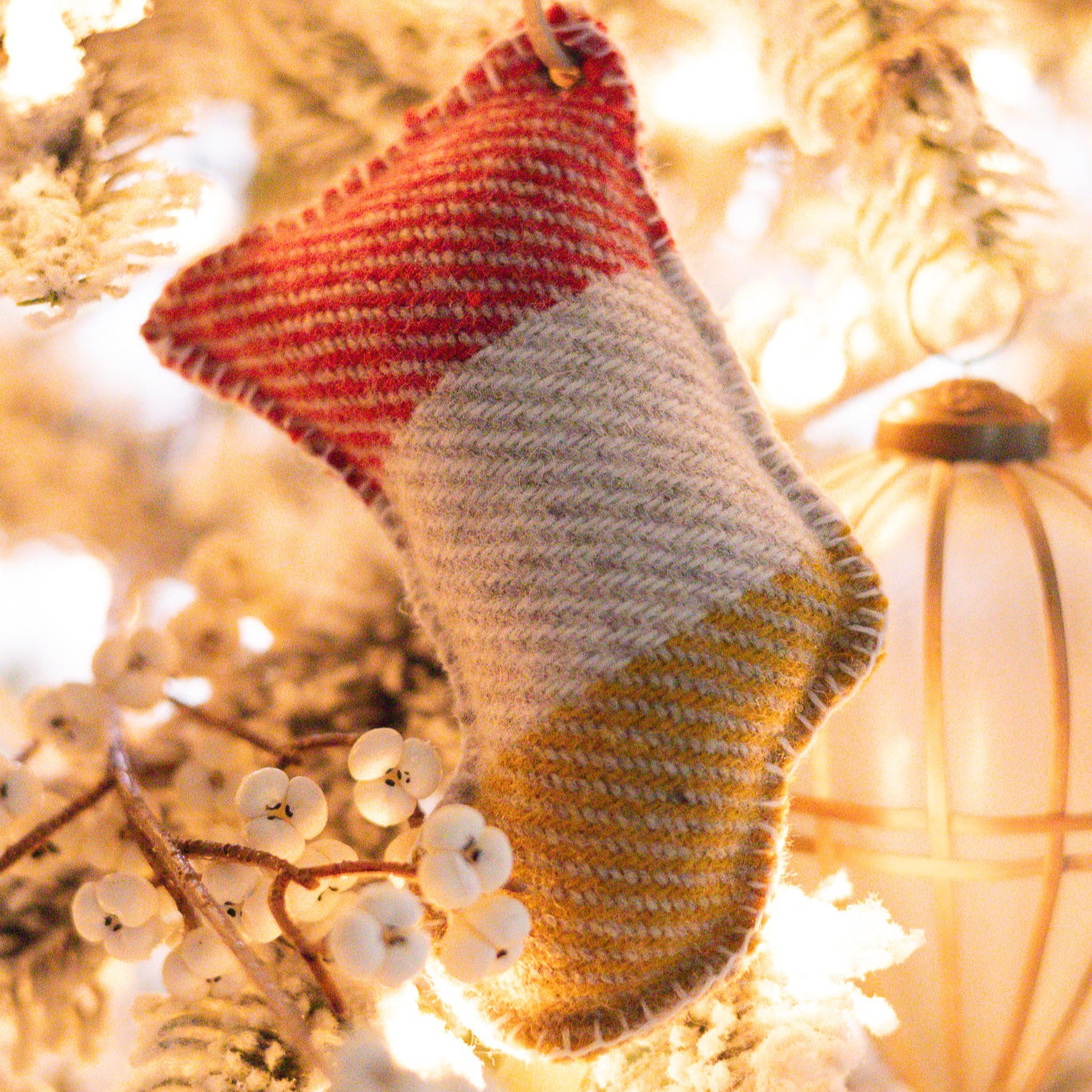 Pendleton wool ornament hanging on a branch with blurred lights in the background
