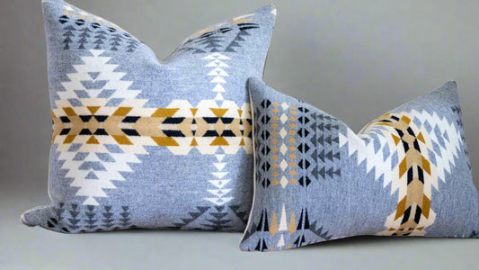 Two patterned pillows on a couch against a white wall