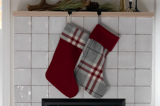 Red and gray plaid stockings hanging above a fireplace with decorative antlers on the mantel.