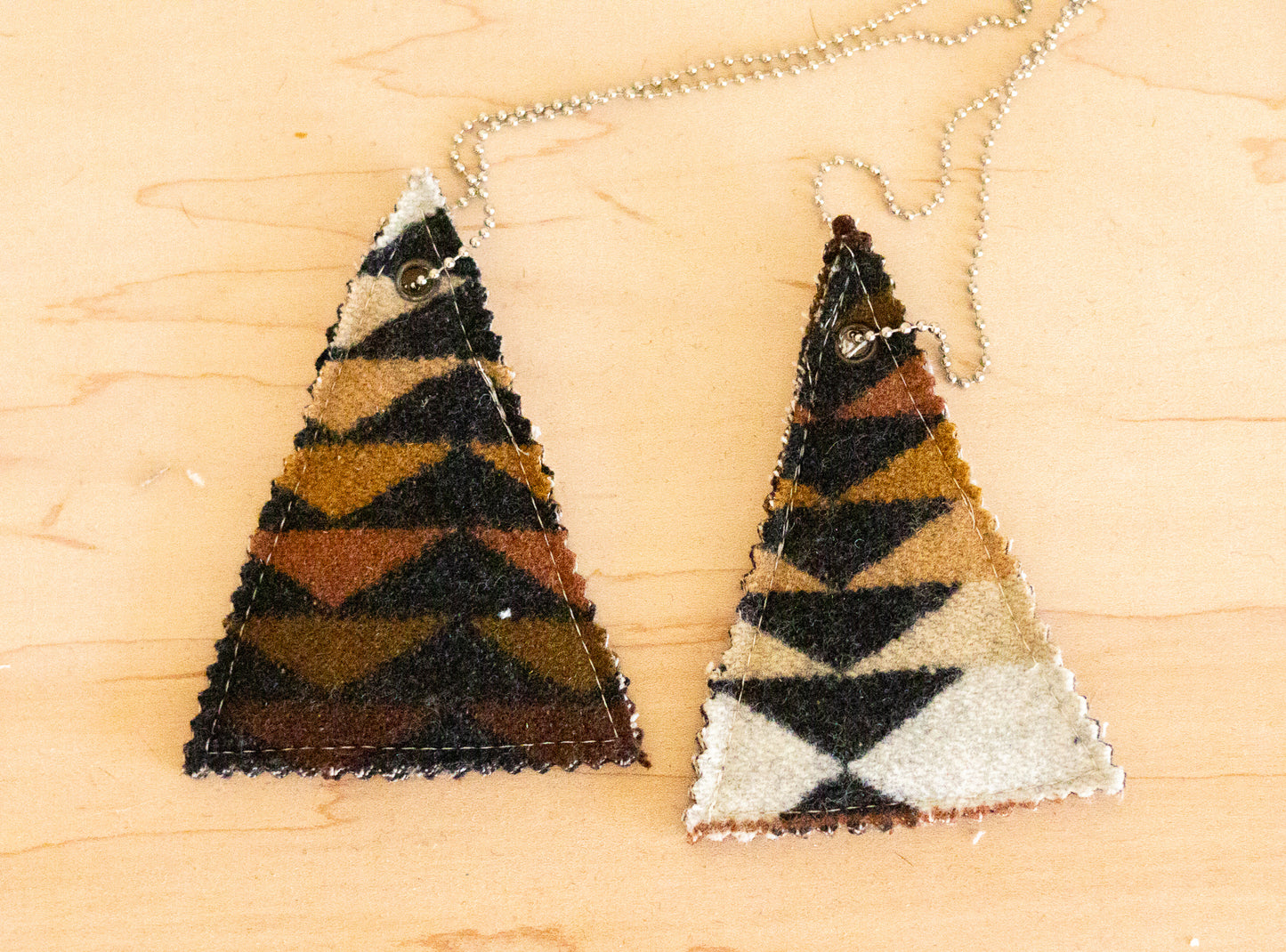 Two triangular air fresheners with zigzag pattern on a wooden surface