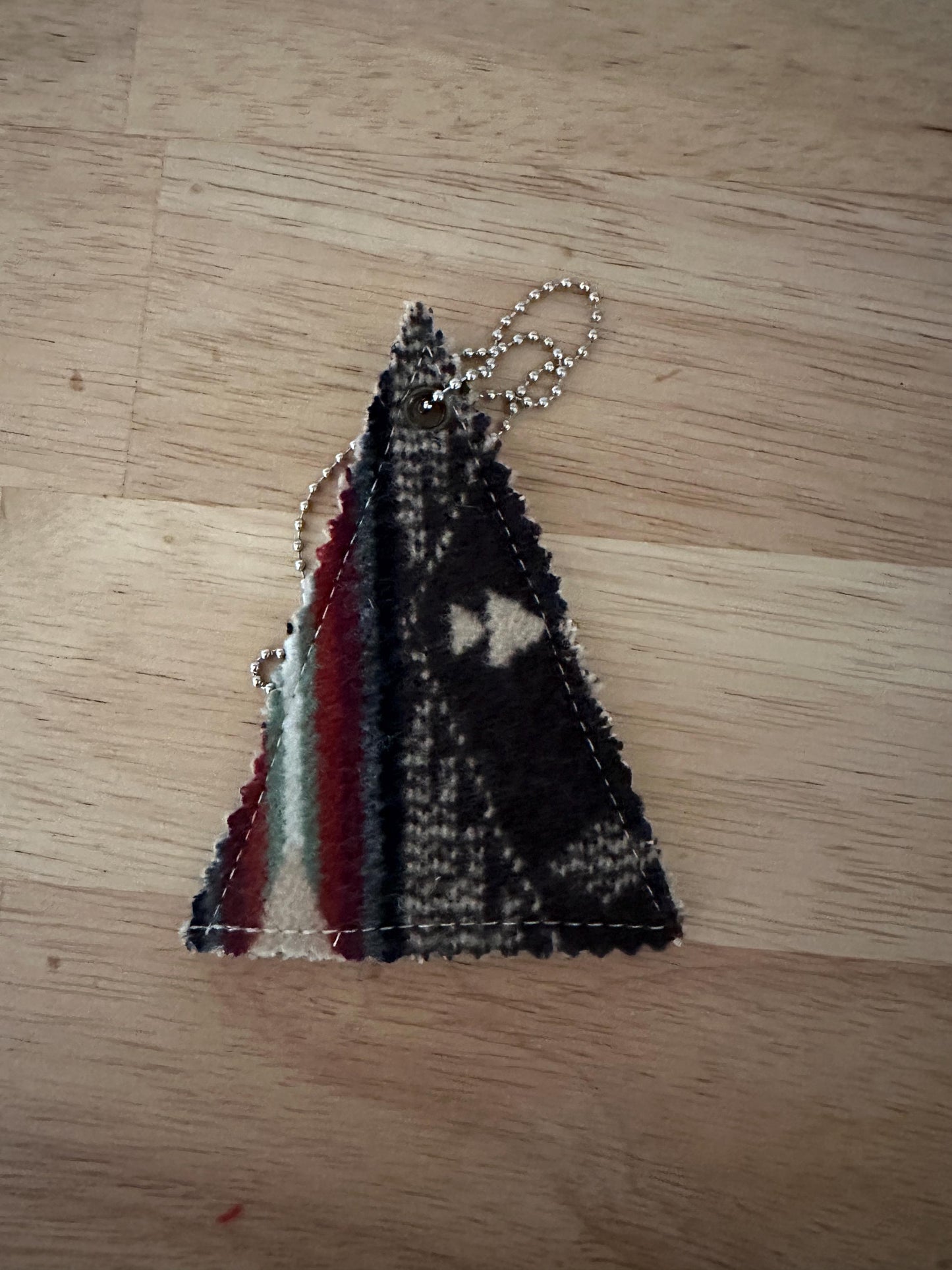 Triangular woven keychain on a wooden surface