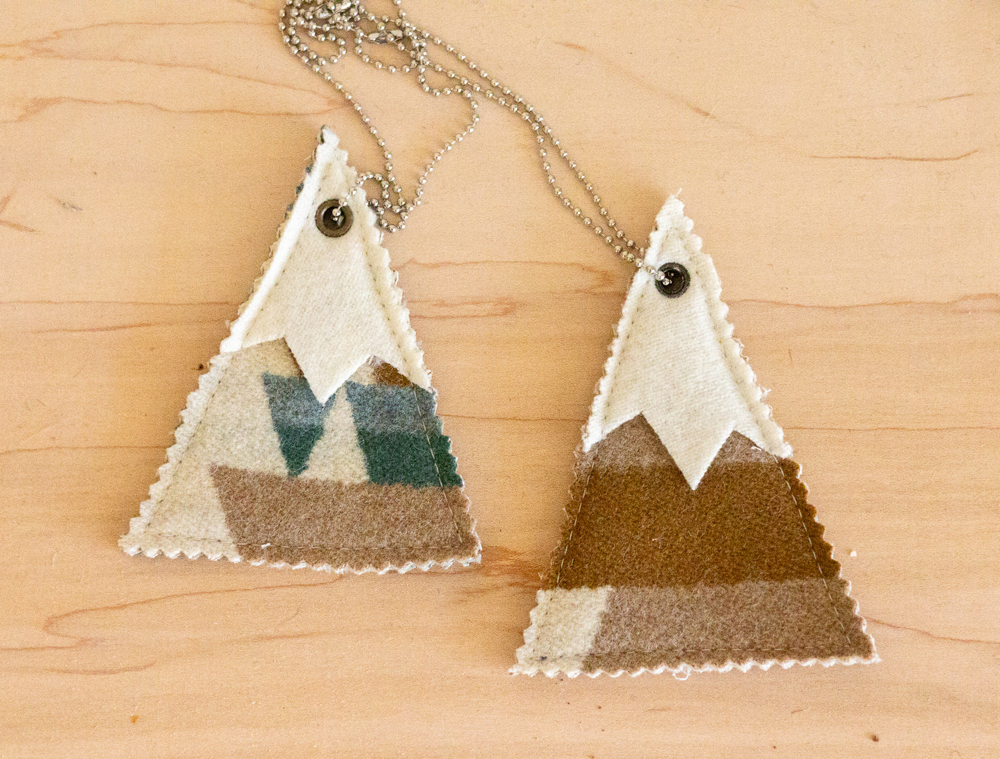 Two triangle-shaped air fresheners with striped patterns on a wooden surface
