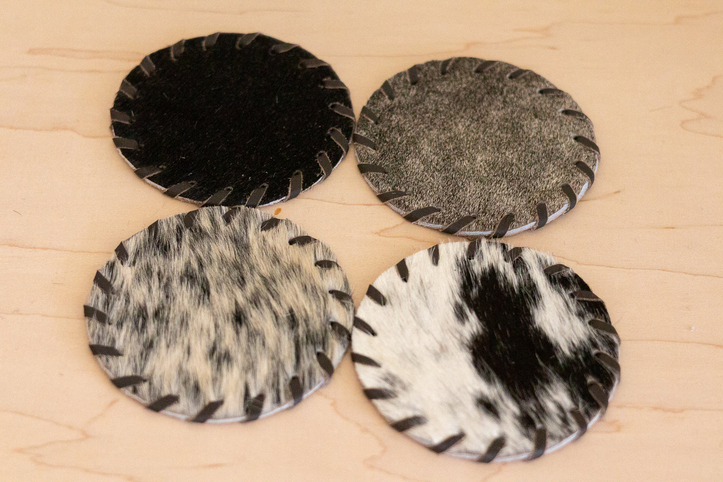 Four round coasters with different patterns on a wooden surface