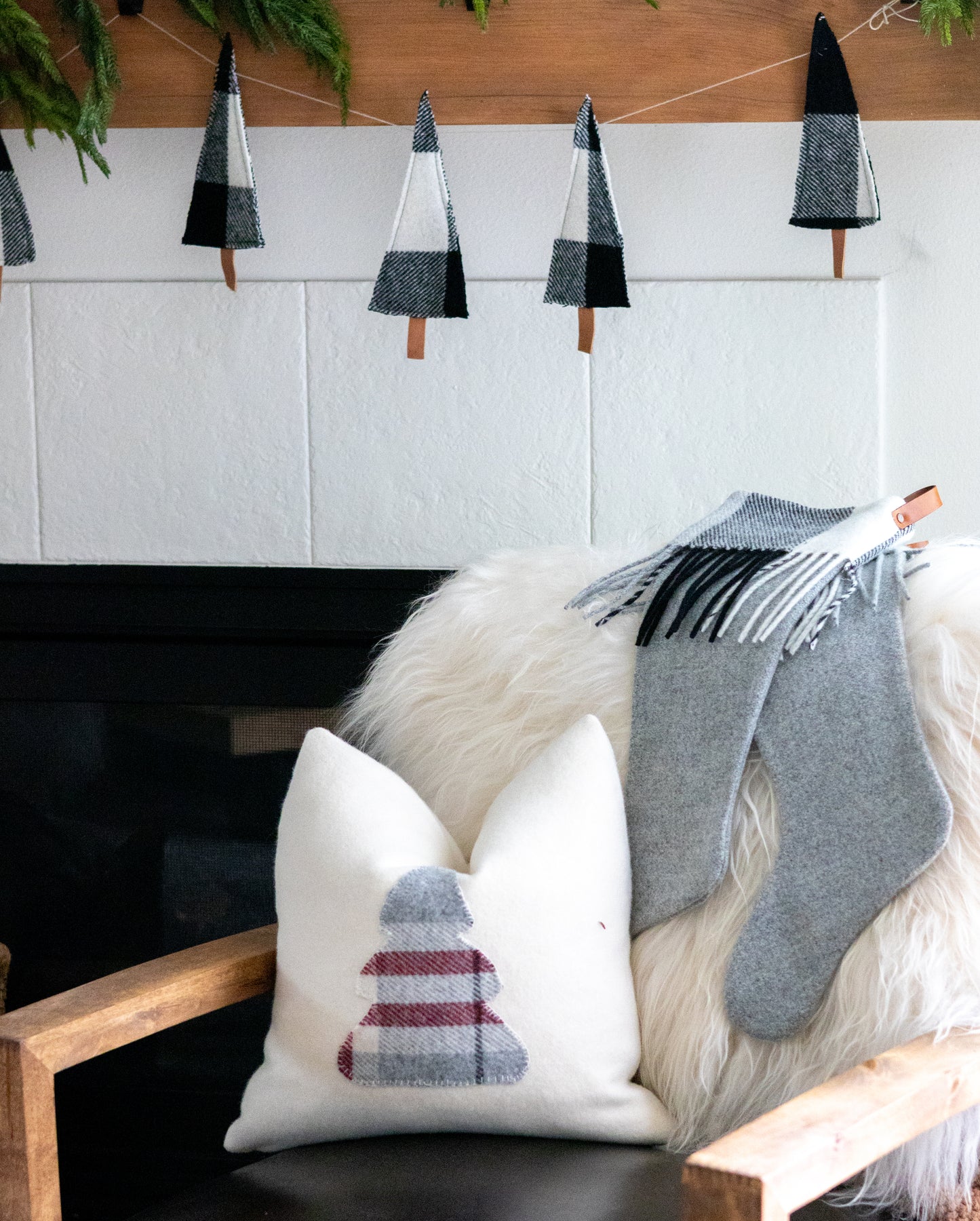 Decorative pillows and stockings on a sofa with Christmas tree decorations in the background.