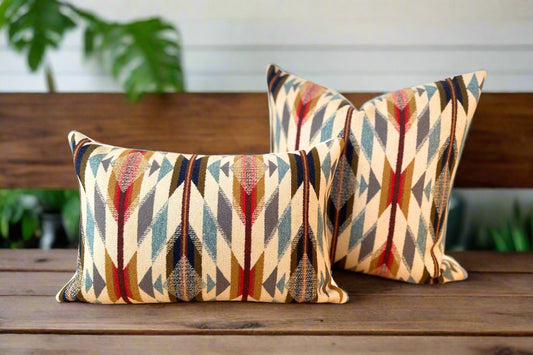 Two patterned pillows on a wooden surface with a plant in the background