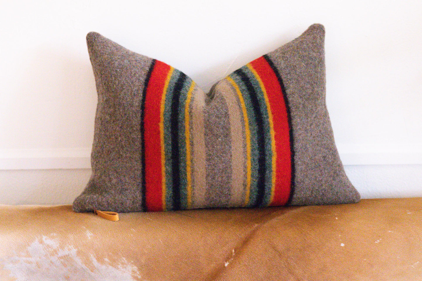 Striped pillow with red, yellow, and blue accents on a brown couch.