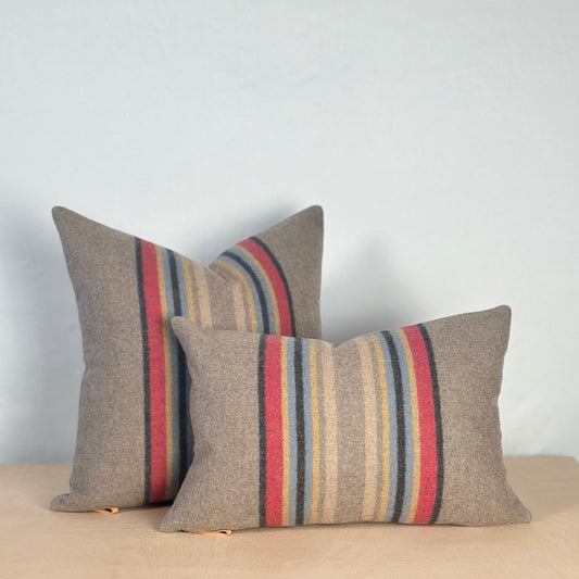Two striped pillows on a beige surface with a light gray background