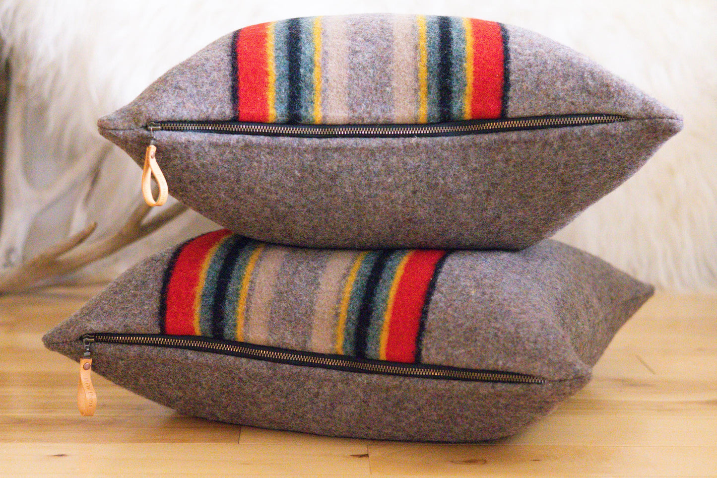 Two brown pillows with colorful striped patterns stacked on a wooden surface.